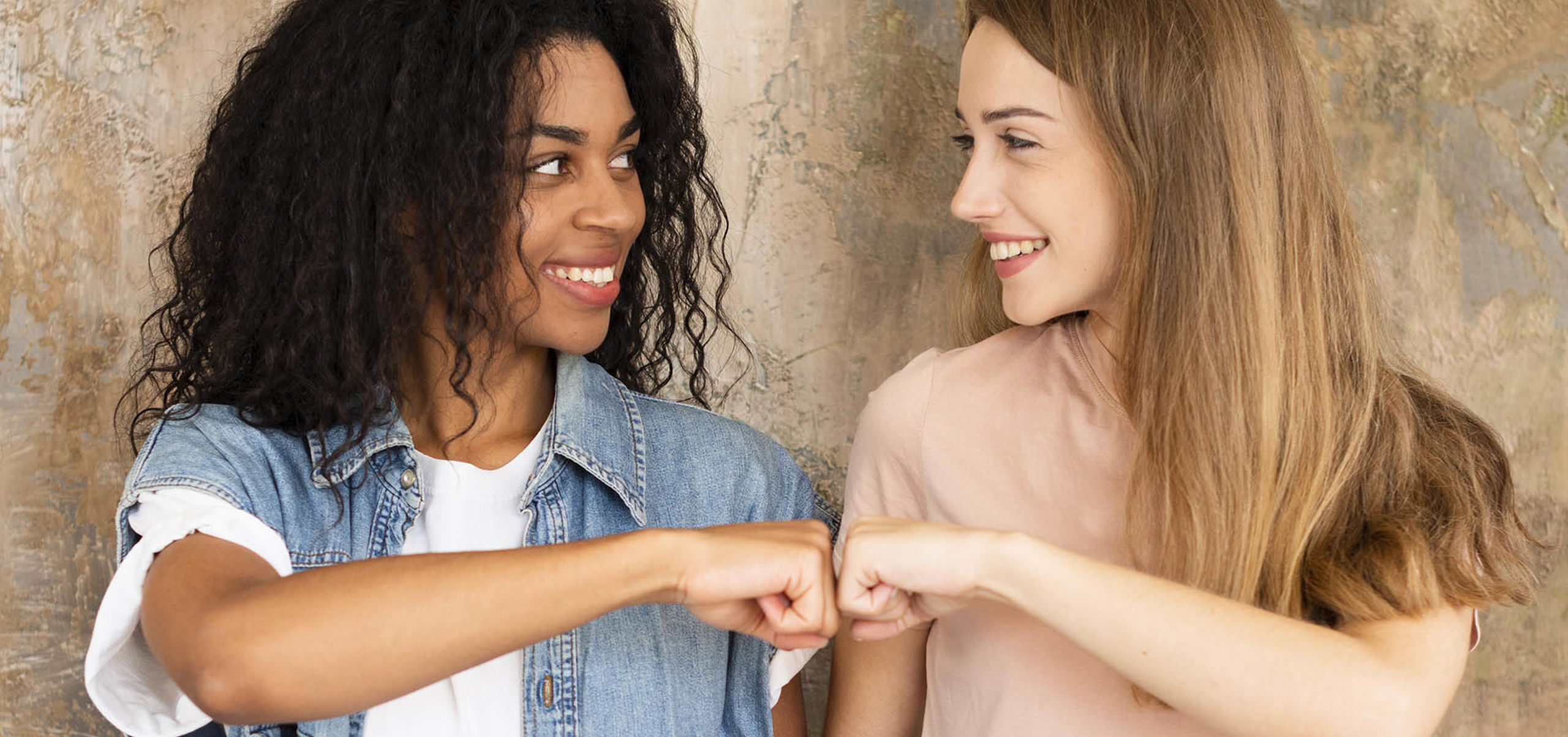 Smiley female friends fist bumping