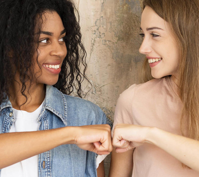 Smiley female friends fist bumping
