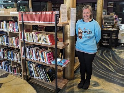 Amy Costa standing next to her book library
